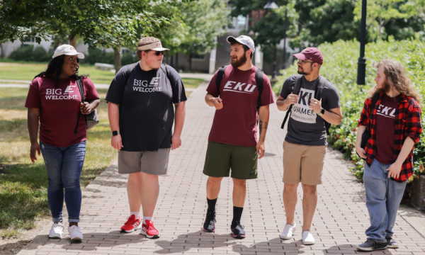 A line of five students walking and wearing EKU gear on EKU campus.