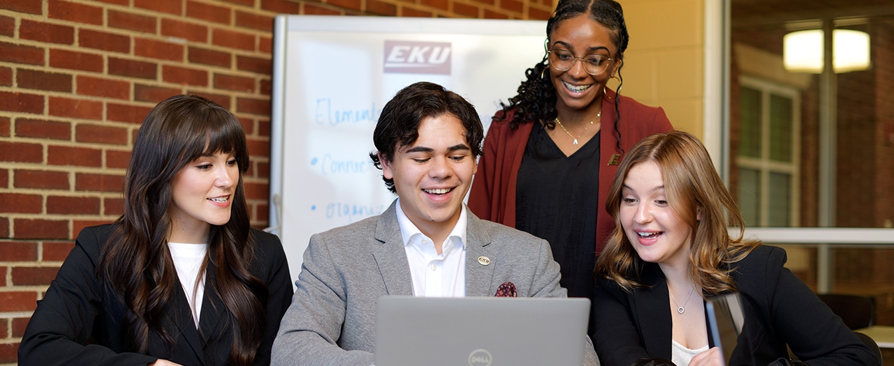 A group of EKU students sitting in the business building around a computer