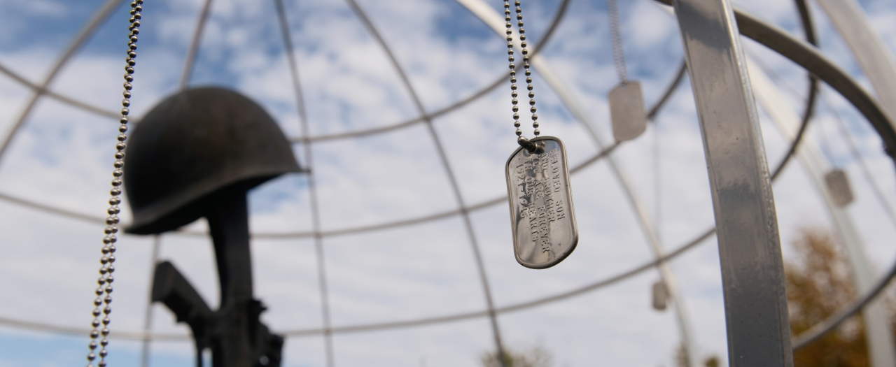 Silver Dog tags handing around a metal globe with a memorial inside.