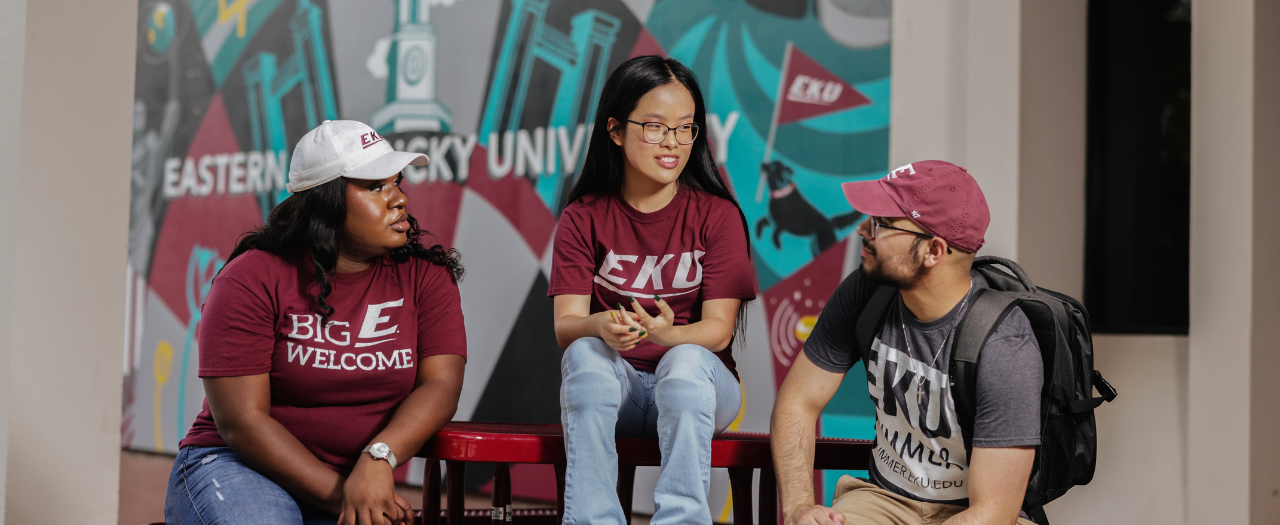 Students sitting in front of an Eastern Kentucky University mural