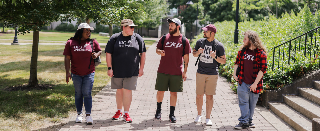 A line of five students walking and wearing EKU gear on EKU campus.