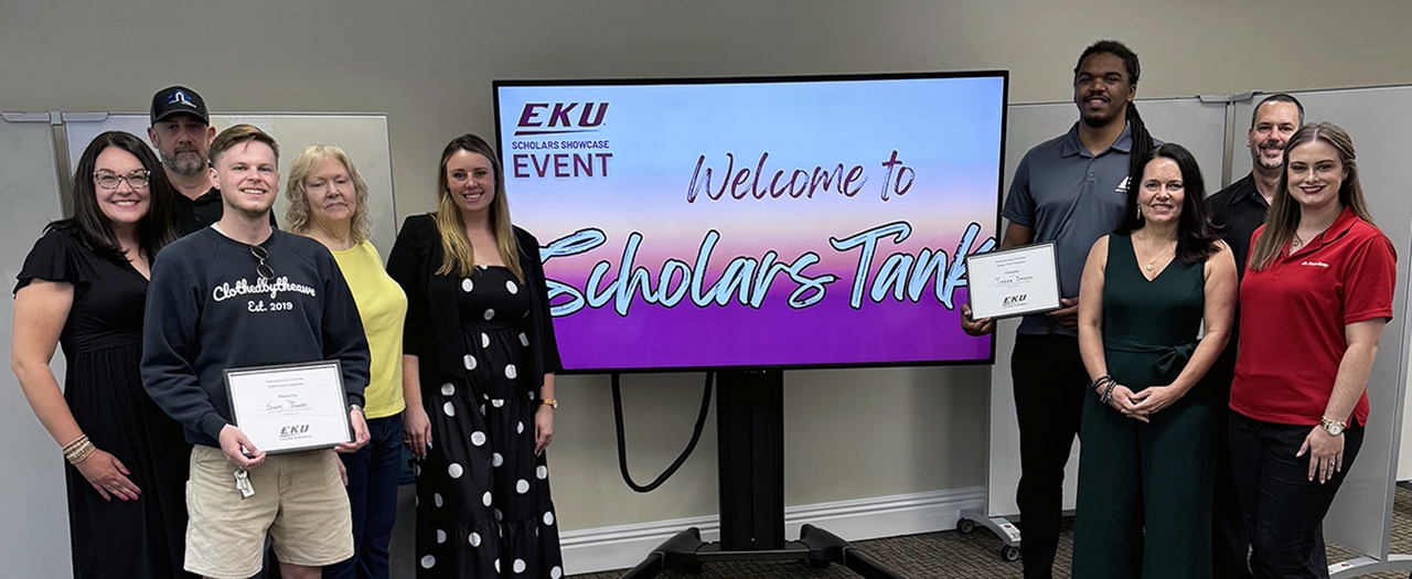 Participants Standing by screen displaying Welcome to EKU Scholars Tank