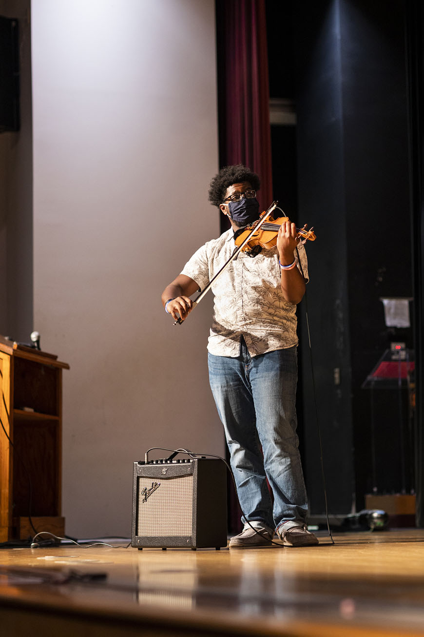 Student playing violin on stage during talent show